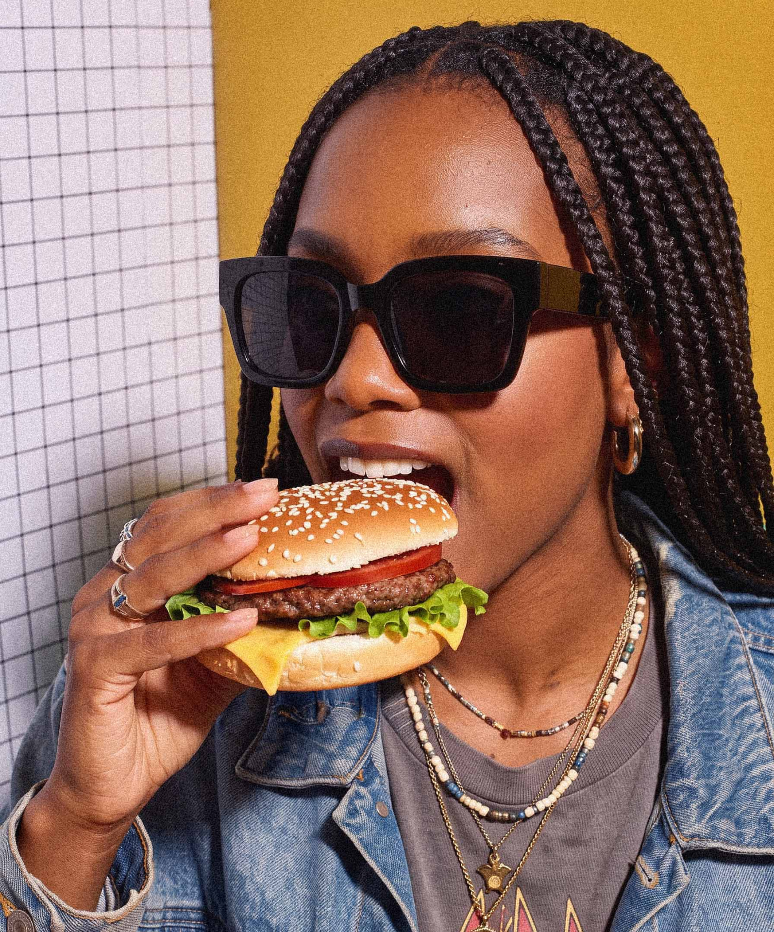 A guest in sunglasses taking a big bite of a cheeseburger